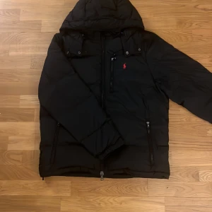 Svart vinterjacka från Polo Ralph Lauren - Säljer en snygg svart jacka från Polo Ralph Lauren i nytt skick. Jackan har en klassisk pufferstil och Perfekt för kalla vinterdagar. Fick jackan i present men den var för stor så säljer den eftersom dom inte hade kvar kvitto.