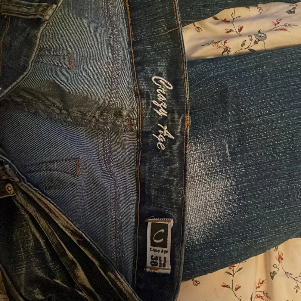 Snygga blå jeans från Crazy Age med coola broderade detaljer på framsidan och bakfickorna. De har en klassisk femficksdesign och dragkedjor på bakfickorna för extra stil. dm för flera bilder eller frågor! st38 men passar 36. Jeans & Byxor.