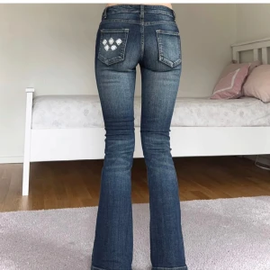 Blå bootcut jeans med broderi - Säljer ett par snygga blå bootcut jeans i bra skick. De har ett coolt broderi på bakfickorna och en klassisk femficksdesign. Perfekta för både vardag och fest! 😊