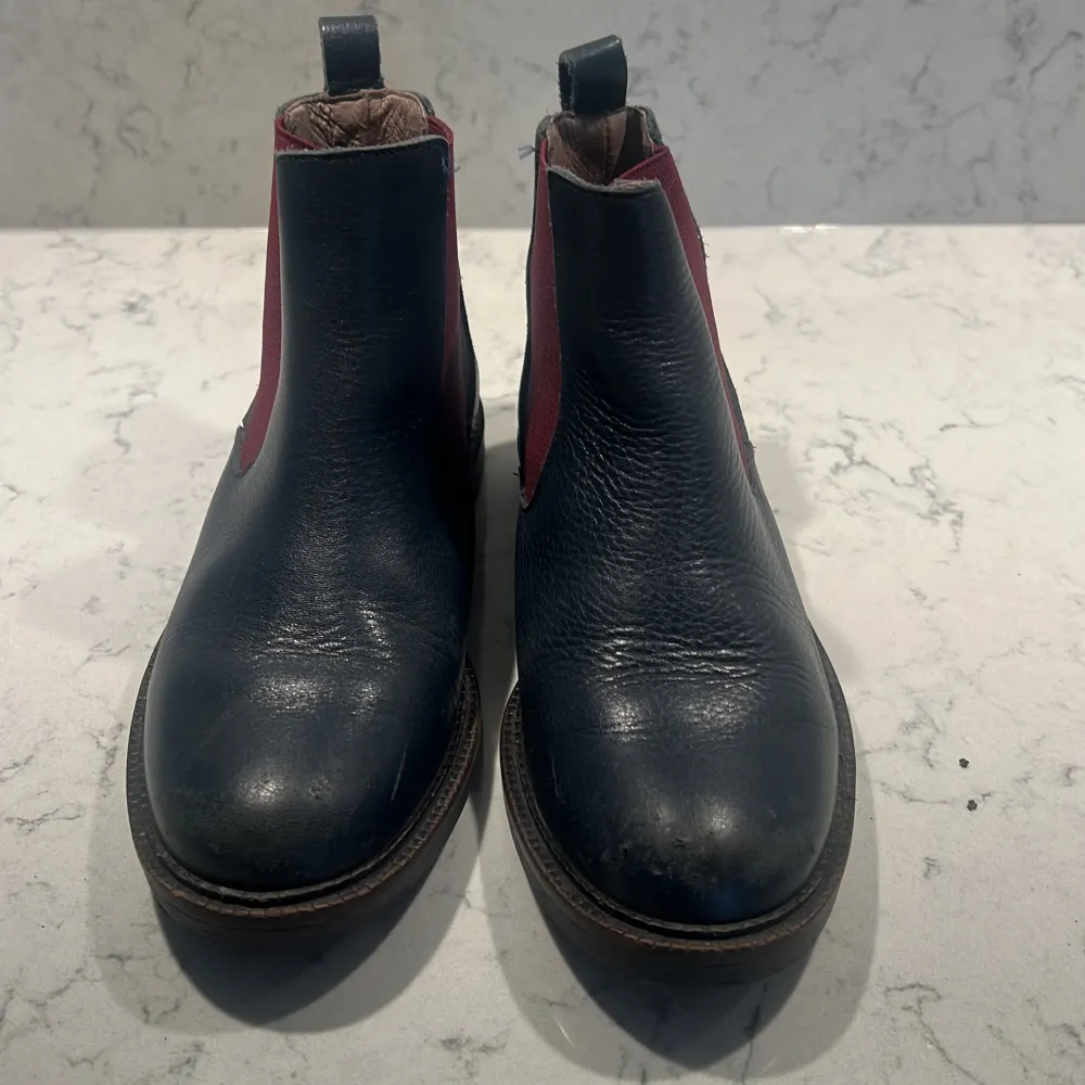 Säljer ett par snygga svarta Chelsea boots i skinn med en cool röd resårdetalj på sidan från Bonpoint. Skorna är använda därav priset.. Skor.