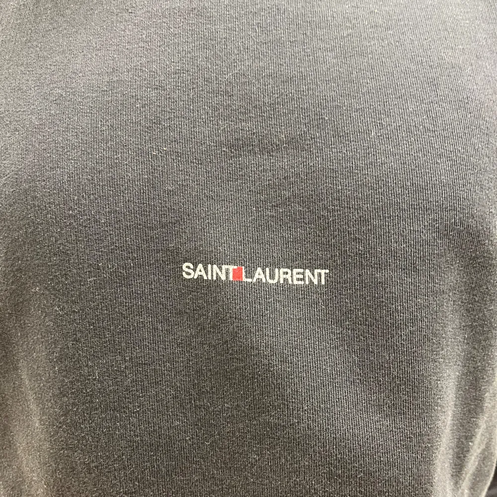 Säljer en stilren svart hoodie från Saint Laurent. Den har en klassisk design med en justerbar huva. Perfekt för en avslappnad och trendig look. Passar till alla tillfällen! modellen på bilden är 185cm. Tröjor & Koftor.