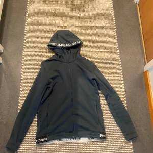 Mörkblå hoodie från Peak Performance - Säljer en snygg blå hoodie från Peak Performance. Den är perfekt för både träning och vardag med sin bekväma passform. Hoodien har långa ärmar och en stilren design med loggan tryckt på huvan och nederkanten. Materialet känns mjukt och skönt mot hud