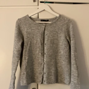 Grå kofta från lager157 - Säljer en supermysig grå kofta från lager 157 i storlek XS. Den är stickad och har långa ärmar med knappar hela vägen fram. Perfekt för höst och vinter när du vill hålla dig varm och stilren. Koftan är i bra skick och passar till alla tillfällen!