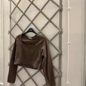 Tröja aimn - Snygg brun topp med långa ärmar och en kvadratisk halsringning. Toppen är figursydd och har en kort längd. Den är aldrig använd!