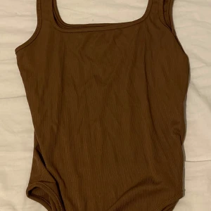 Brun ribbad bodysuilt - Snygg brun baddräkt med ribbad textur och fyrkantig urringning. Perfekt för sommar.