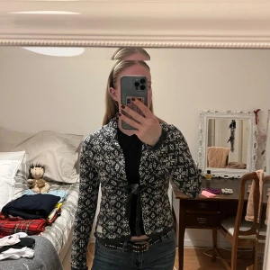 Svartvit mönstrad kofta från Odd Molly - Säljer en snygg svartvit kofta med ett geometriskt mönster. Koftan har långa ärmar och knyts med ett band framtill. Perfekt för att hålla sig varm och stilren. 