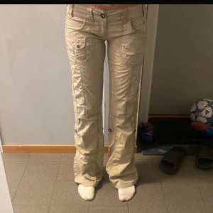 Lågmidjade cargopants  - Säljer ett par beige cargopants från Esprit med flera fickor och knappdetaljer. Byxorna är lågmidjade!!