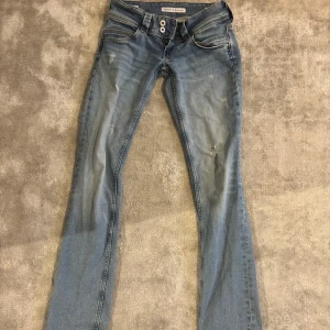 Pepe Jeans Venus lågmidjade slitningar  - Ljus blå lågmidjade jeans från Pepe Jeans i modellen Venus straight med slitningar/hål. Storlek W25L32 