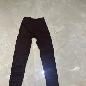 Bruna leggings från Gymshark - Snygga bruna leggings från Gymshark med hög midja och ett diskret mönster. Perfekta för träning med en tight passform som ger bra stöd. Tillverkade i ett stretchigt material för maximal komfort.