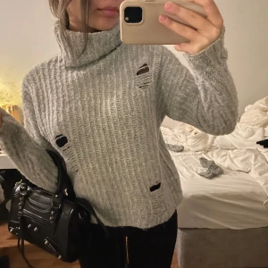 Grå ribbad polotröja - SÅ SÅ SÅ SÅ SNYGG 😋Säljer en grå ribbad polotröja med slitna detaljer. Tröjan har en hög krage och långa ärmar, perfekt för en avslappnad stil. Perfekt för att känna sig bekväm men samtidigt snygg !!!
