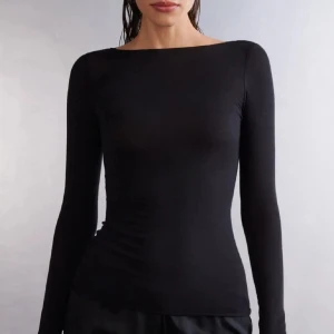 Svart långärmad topp - Säljer en stilren svart långärmad topp med en elegant passform. Perfekt för att matcha med olika outfits. Toppen har en enkel design som gör den mångsidig och lätt att bära. Liknande intimissimi.
