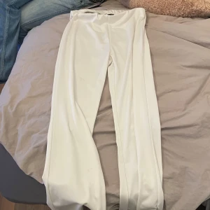 Vita byxor - Snygga vita byxor med hög midja och rak passform. Perfekta för en stilren look. Tillverkade i ett mjukt och bekvämt material.