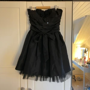 Svart klänning - Svart axelbandslös klänning från Goddess London med volangdetaljer och knytband i midjan. Mini klänning i storlek s/m perfekt nu till ny år💗