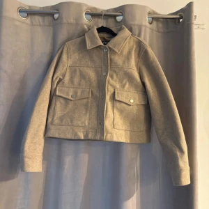 Beige jacka från Zara - Snygg beige jacka från Zara med knappar framtill och två stora fickor. Perfekt för höst och vår. Jackan har en klassisk krage och är långärmad, vilket gör den både stilren och praktisk. Passar mer om man har storlek XS/S 