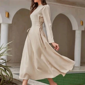 Beige långklänning med snörning - Elegant beige långklänning med långa ärmar och snörning i midjan. Storlek S, aldrig använt endast testat och storleken passade inte mig. Köpt för 349kr säljer för endast 250kr. Kom gärna med prisförslag