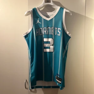 Turkos Charlotte Hornets basketlinne - Säljer ett turkost Charlotte Hornets basketlinne med nummer 3 och namnet Rozier III. Linnet är från Jordan och har vita ränder samt Dri-FIT material för optimal komfort. Perfekt för basketfans och sportentusiaster!