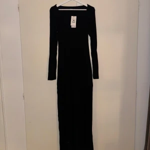 Svart långklänning - Elegant svart långklänning med långärmad design. Perfekt för en stilren och sofistikerad look. Klänningen har en figurnära passform som framhäver silhuetten.
