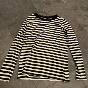 Randig långärmad tröja - Säljer en svartvit randig långärmad tröja i mycket bra skick. Perfekt för både vår och höst, med en skön passform som funkar till det mesta. Den är gjord i mjukt material och har en klassisk stil som aldrig går ur tiden. Passar lika bra till jeans som till kjol!