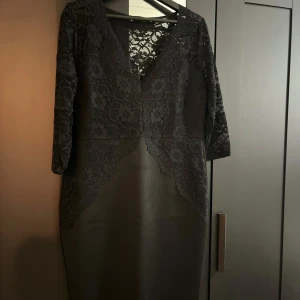 Svart spetsklänning från Dorothy Perkins - Elegant svart klänning från Dorothy Perkins i storlek L. Klänningen har en vacker spetsdesign med trekvartsärmar och en stilren v-ringning. Perfekt för festliga tillfällen eller en utekväll. Tillverkad i Storbritannien.