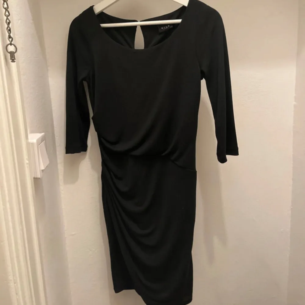 Klänning i polyester. Fin modell med snygg skärning. . Mekot.