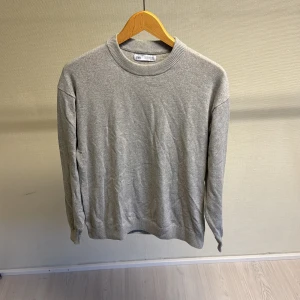 Grå tröja från Zara - Säljer en stilren grå tröja från Zara i storlek 13-14 år. Perfekt för både vardag och skola. Tröjan är i ett mjukt material och har en klassisk rund halsringning. Den är långärmad och passar bra till både jeans och chinos. Ett måste i garderoben för en enkel och snygg look!