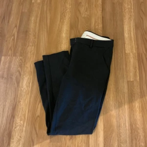 Mörkgrå kostymbyxa - Mörkgrå Kostymbyxa i filtmaterial. De har fickor fram och fuskfickor bak. Passformen är avsmalnande 