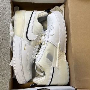 Vita Nike Air sneakers/ Nike Air Force 1 React "40th Anniversary" - Säljer ett par fräscha vita Nike Air sneakers i syntetmaterial. De har snygga svarta detaljer och prickiga flikar baktill. Skorna har klassisk snörning och en stilren design som passar perfekt till vardags☺️. De är i mycket bra skick och redo för nya äventyr!/ aldrig använt då den är för stor❗️