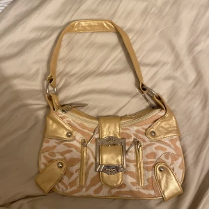 90s tal väska - Jag säljer en väska som jag har aldrig använt ,jag fick den av min mamma men den har aldrig kommit till användning. Den  är i färgen guld och har bra skick