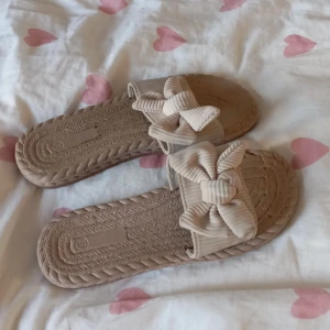 Beige sandaler med rosett - Säljer ett par söta beige sandaler med en stor rosett på ovansidan. Perfekta för sommardagar och strandhäng. De är bekväma och lätta att bära, med en flätad sula som ger en bohemisk känsla. Passar bra till både klänning och shorts.