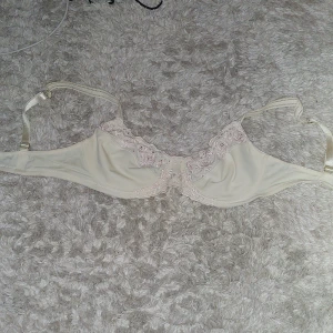 Beige bh med spetsdetaljer - Elegant beige bh med vackra spetsdetaljer längs kanterna. Justerbara axelband för perfekt passform. Perfekt för en stilren och bekväm look.
