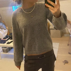 Grå stickad tröja - Mysig grå stickad tröja med rund halsringning och långa ärmar. Perfekt för kyligare dagar och enkel att matcha med olika outfits.