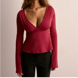 Vinröd topp med öppen rygg och rosett - Snygg vinröd topp med djup v-ringning och långa ärmar. Helt ny från Nelly! lappar kvar! Ord pris 299