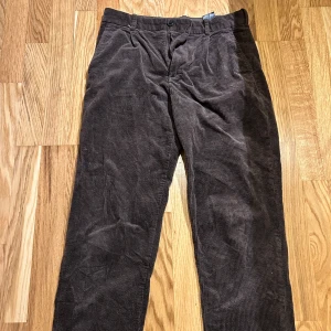 Bruna manchesterbyxor - Snygga bruna manchesterbyxor med hög midja och rak passform. Perfekta för en stilren look med en skön känsla. Byxorna har knappar och dragkedja framtill samt fickor både fram och bak.