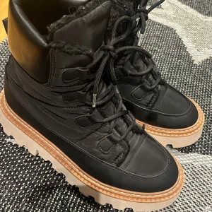 Svarta boots med snörning - Snygga svarta boots med snörning och grov sula. De har en vadderad krage och är perfekta för kyligare väder. Skorna har en stilren design med en kontrasterande ljus sula. Det är inte använda super mycket! Ingen aning va de är för märke, köpta för 1000kr