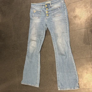Blå jeans från Lois - Snygga blå jeans från Lois med hög midja och bootcut-stil. Snygga detaljer som fem fickor och knappar framtill. Perfekta för en avslappnad look. 