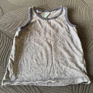 Grå linnetopp - Säljer en enkel och bekväm grå linnetopp med mörkare grå kant vid ärmhål och hals. Perfekt för varma dagar eller som lager under andra plagg.
