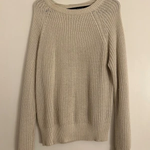 Beige stickad tröja från Collection - Säljer en stilren beige stickad tröja från Lager 157. Tröjan har en klassisk design med långa ärmar och ribbade kanter vid ärmslut och nederkant. Perfekt för kyligare dagar. Tröjan är i storlek M men kan användas som en oversize för xs