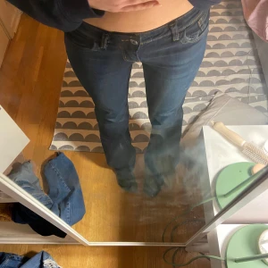 Mörkblå jeans med bootcut - Säljer ett par mörkblå jeans med bootcut och snygga sömmar på bakfickorna. Jeansen har en lågmidjad passform och klassisk femficksdesign. Perfekta för en avslappnad stil.