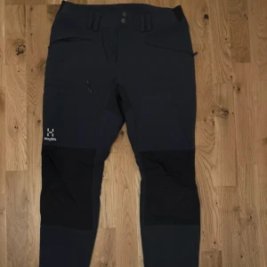 byxor från Haglöfs - Säljer ett par byxor från Haglöfs med dragkedja och knappar. Byxorna har förstärkta partier och är perfekta för utomhusaktiviteter. De har en praktisk ficka med dragkedja på sidan.         Haglöfs mid slim pants i storlek 48.