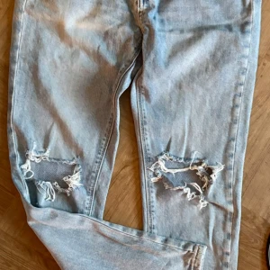 Ljusa jeans från Milk Atelier - Snygga ljusa jeans från Milk Atelier med slitna detaljer på knäna. De är tillverkade av 99% bomull och 2% spandex för en bekväm passform. Perfekta för en avslappnad stil.