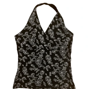 Svart halterneck topp från New Look - Snygg svart halterneck topp från New Look med ett vackert vitt blommönster. Strl 12 på lapp men mer en S i size. 