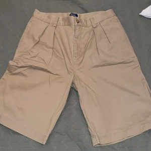 Beige shorts från Polo Ralph Lauren - Snygga beige shorts från Polo Ralph Lauren i 100% bomull. De har en klassisk design med knappar och dragkedja framtill samt fickor både fram och bak. Perfekta för en avslappnad stil.