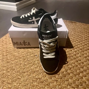 Svarta sneakers från Premiata - Snygga svarta sneakers från Premiata med vita detaljer och snörning. Skorna har en stilren design med märkets logga på sidan och en bekväm sula.