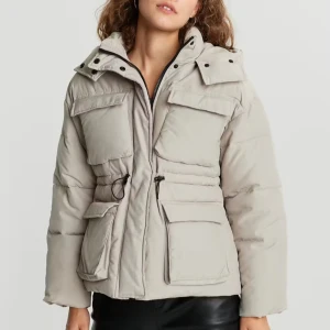 Beige pufferjacka med huva - Snygg beige pufferjacka med huva och dragkedja. Jackan har praktiska fickor och justerbar midja för en bekväm passform. Perfekt för kyliga dagar. Passar S/M.