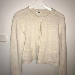 Vit stickad kofta från Uniqlo - Säljer en mysig vit stickad kofta från Uniqlo. Koftan har långa ärmar, knappar framtill och praktiska fickor. Perfekt för kyliga dagar!
