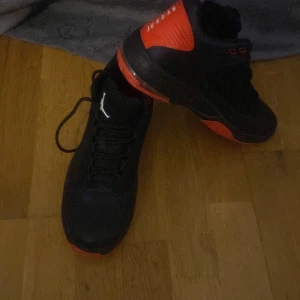 Svarta och röda Nike Air Jordans - Säljer ett par svarta Nike Air Jordans med röda detaljer. Skorna har snörning och den klassiska Jumpman-loggan på plösen. Perfekta för dig som vill ha en stilren och sportig look.
