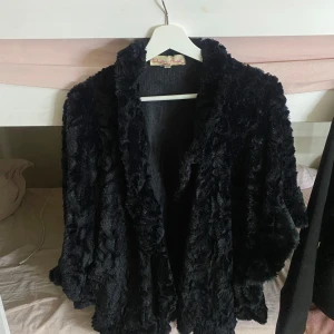Svart pälsjacka från Daisy Street - Mysig svart pälsjacka från Daisy Street. Perfekt för att hålla sig varm och stilren under kyliga dagar. Jackan har en fluffig textur och en avslappnad passform.