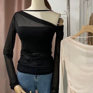 Svart oneshoulder topp - Trendig svart oneshoulder topp med lång ärm och transparenta detaljer. Perfekt för en stilren och modern look.