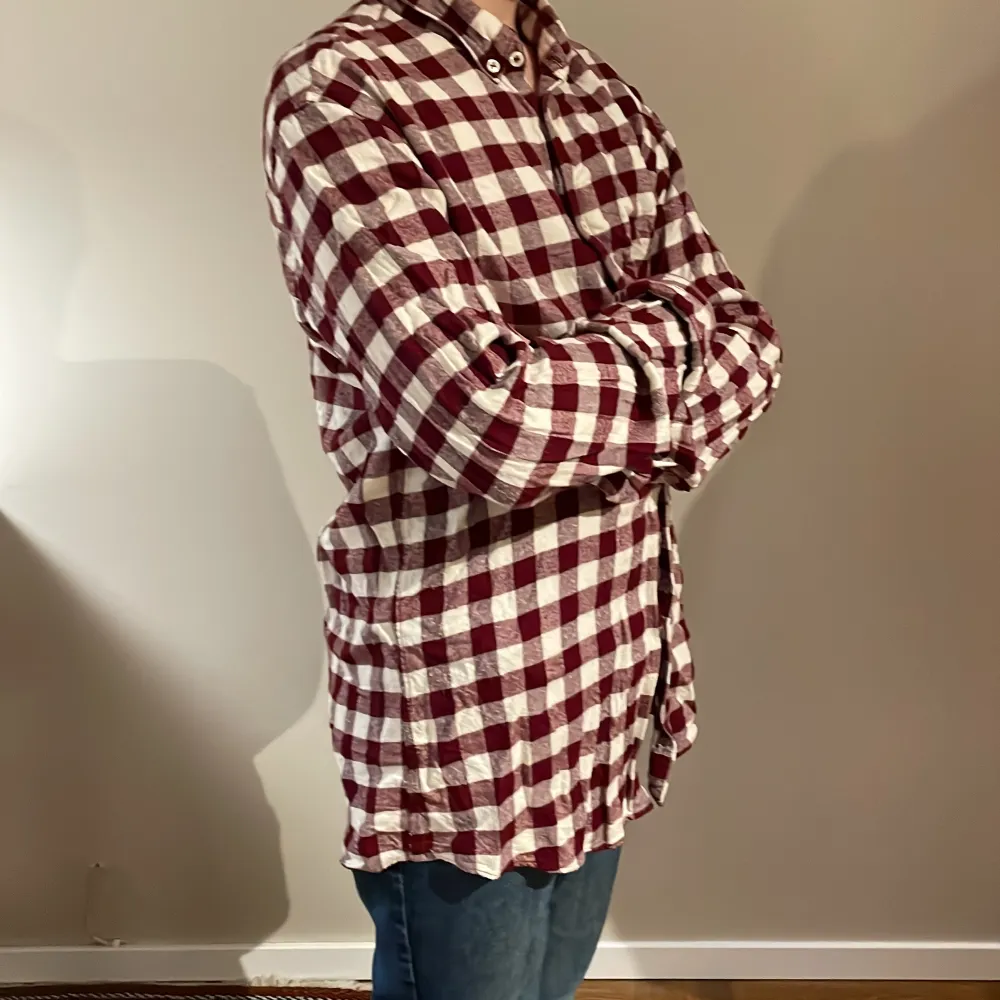Säljer en rutig skjorta från Zara Man i avslappnad passform. Skjortan har ett klassiskt rutmönster i vinrött och vitt, med långa ärmar och knappar framtill. Perfekt för en stilren och bekväm look.. Paidat.