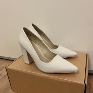 Vita pumps från NLY Shoes - Eleganta vita pumps från NLY Shoes med spetsig tå och hög klack. Perfekta för en stilren look.